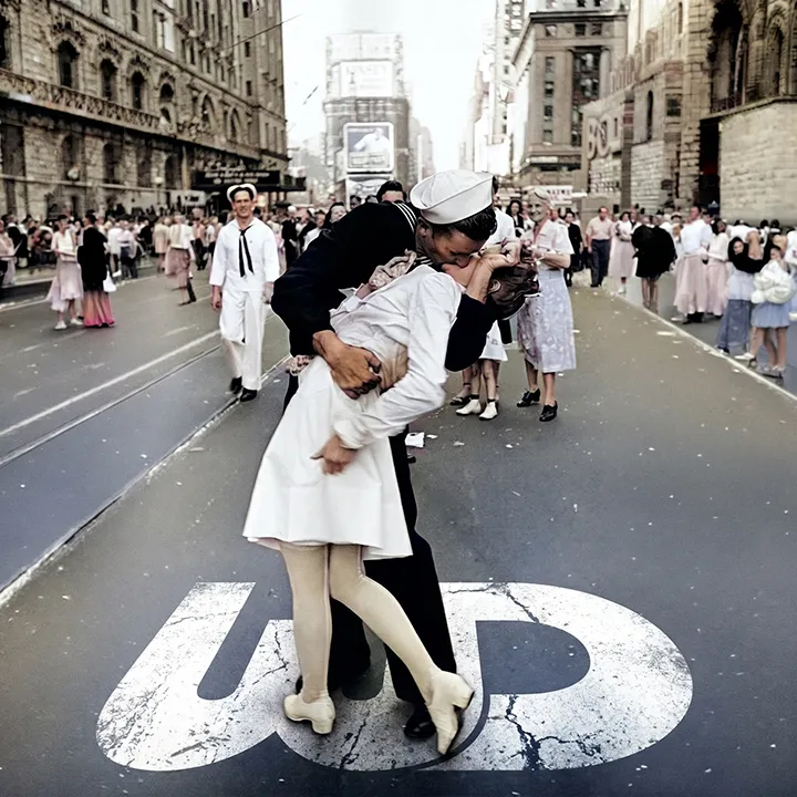 Iconic V-J Day sailor kiss photo in Times Square with a white Womp Designs logo painted on the street.